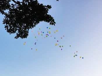 Low angle view of balloons flying against clear blue sky