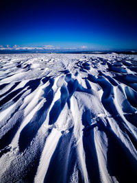 Scenic view of snow covered land against clear blue sky