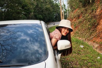 Side view portrait of smiling mature woman leaning out from car window