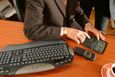 Midsection of businessman using calculator on desk at office