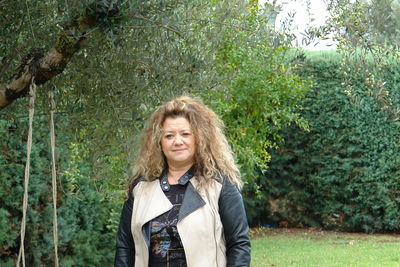 Portrait of a smiling young woman standing against plants