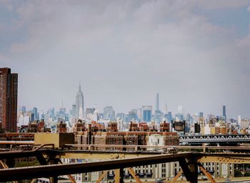 Bridge over river amidst buildings in city against sky