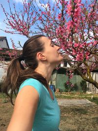 Side view of beautiful woman standing by flower tree