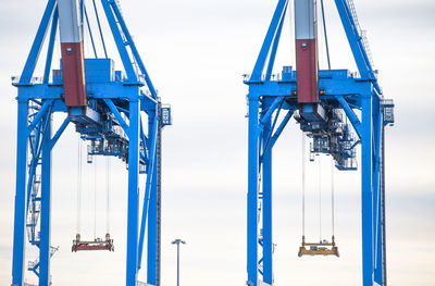 Low angle view of cranes against sky