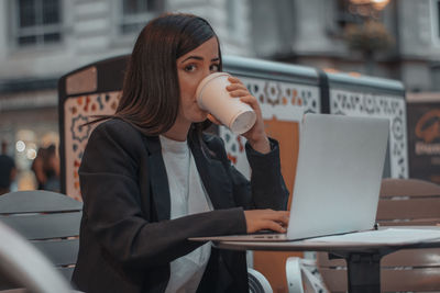 Young businesswoman using laptop while sitting in cafe