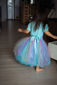 Toddler spinning around while wearing her rainbow dress at home.