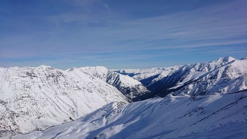 Scenic view of snowcapped mountains against blue sky