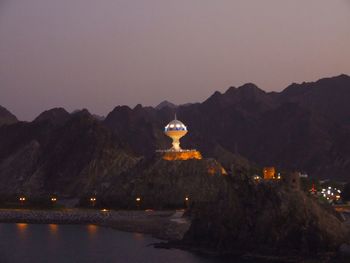 Illuminated mountain range against clear sky at night