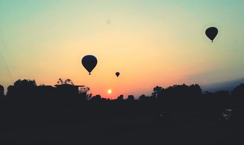 Silhouette hot air balloons against sky during sunset