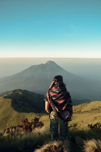 Rear view of man looking at mountain range against sky