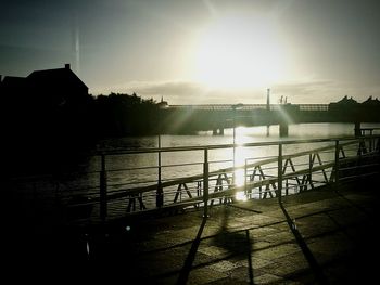 Silhouette of bridge over river during sunset