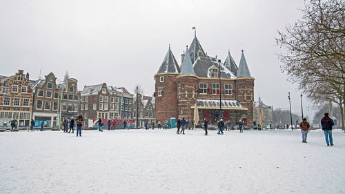 People in front of buildings in city during winter