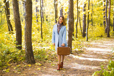 Woman standing by tree trunk in forest