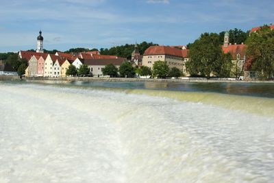 Houses by river at lech against sky