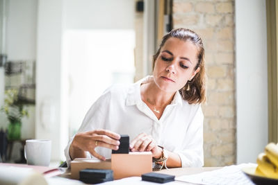 Female designer arranging boxes while sitting at home office