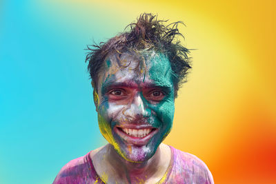 Close-up portrait of indian man covered in holi colors against multicolored background