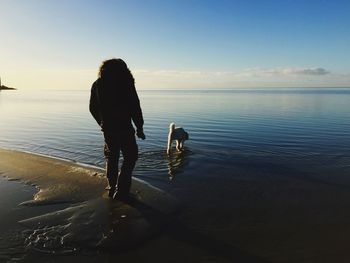 Rear view of woman on beach against sky