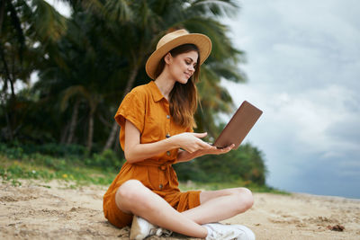 Young woman using mobile phone while sitting on land