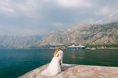 Rear view of woman on sea against mountains