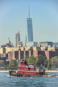 Boats in river with city in background