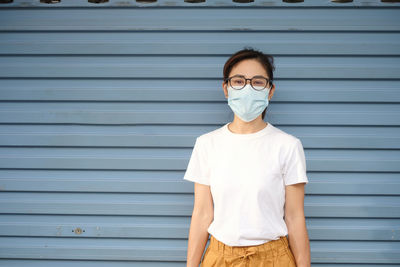 Portrait of boy standing against closed shutter