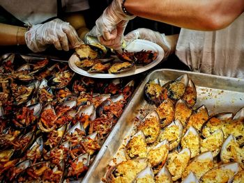 Midsection of people serving cooked mussels