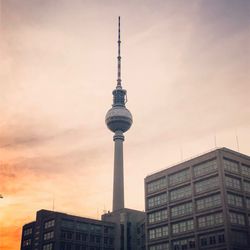 Communications tower in city against sky