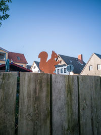 Houses by fence against clear blue sky