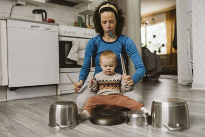 Mature woman and daughter playing with kitchen utensils at home