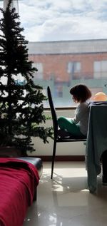 Girl sitting on chair by christmas tree