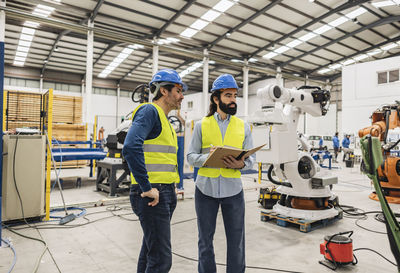 Engineers wearing hardhat examining machines in industry