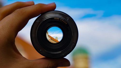 Midsection of person holding camera against sky