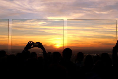 Silhouette people photographing against sky during sunset