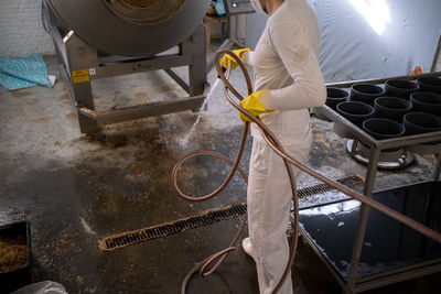 Midsection of man cleaning floor of workshop