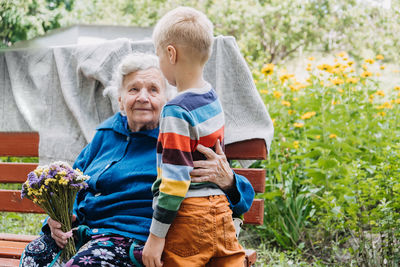 Grandson boy giving a flower to grandma. grandson and grandmother spending time together. granny