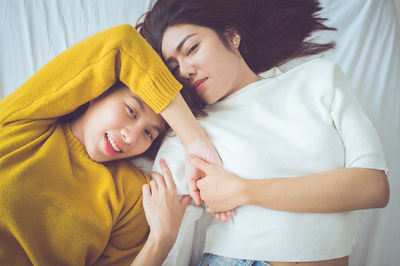 High angle portrait of sisters lying on bed at home