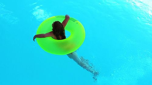 High angle view of girl with inflatable ring swimming in pool