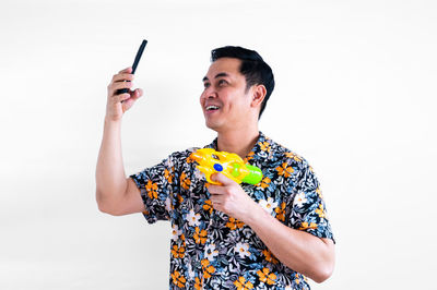 Portrait of smiling young woman with arms raised standing against white background