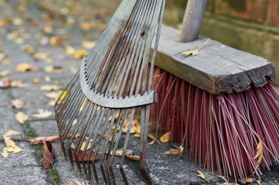 Close-up of broom with rake on footpath during autumn