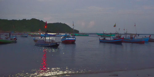 Boats moored in sea against sky at dusk