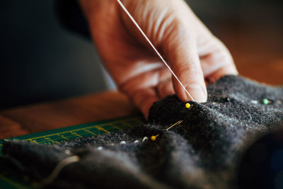 Close-up of cropped hand sewing textile in workshop