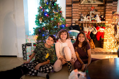 Three siblings smile for the camera on christmas morning