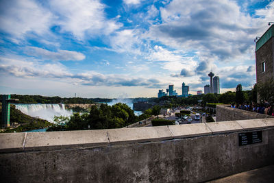 Niagara falls by city against cloudy sky