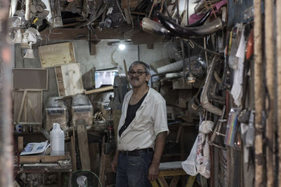 Portrait of mature man standing in messy workshop