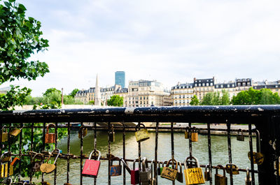 Bridge over river by buildings in city against sky