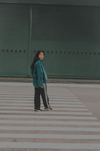 Full length of woman walking against wall