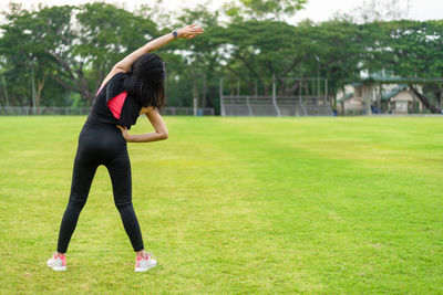 Full length of woman with arms raised on field