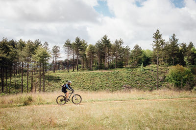 Man cycling bicycle in park against sky