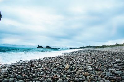 Surface level of pebble beach against sky