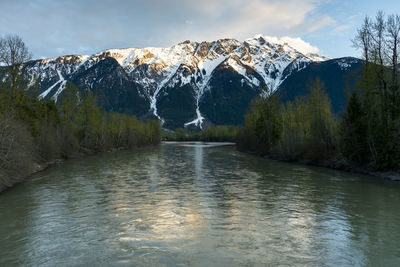 The sun sets on iconic mount currie still covered in snow as the lillooet river flows in the foreground on a spring day in the coast mountains of british columbia.